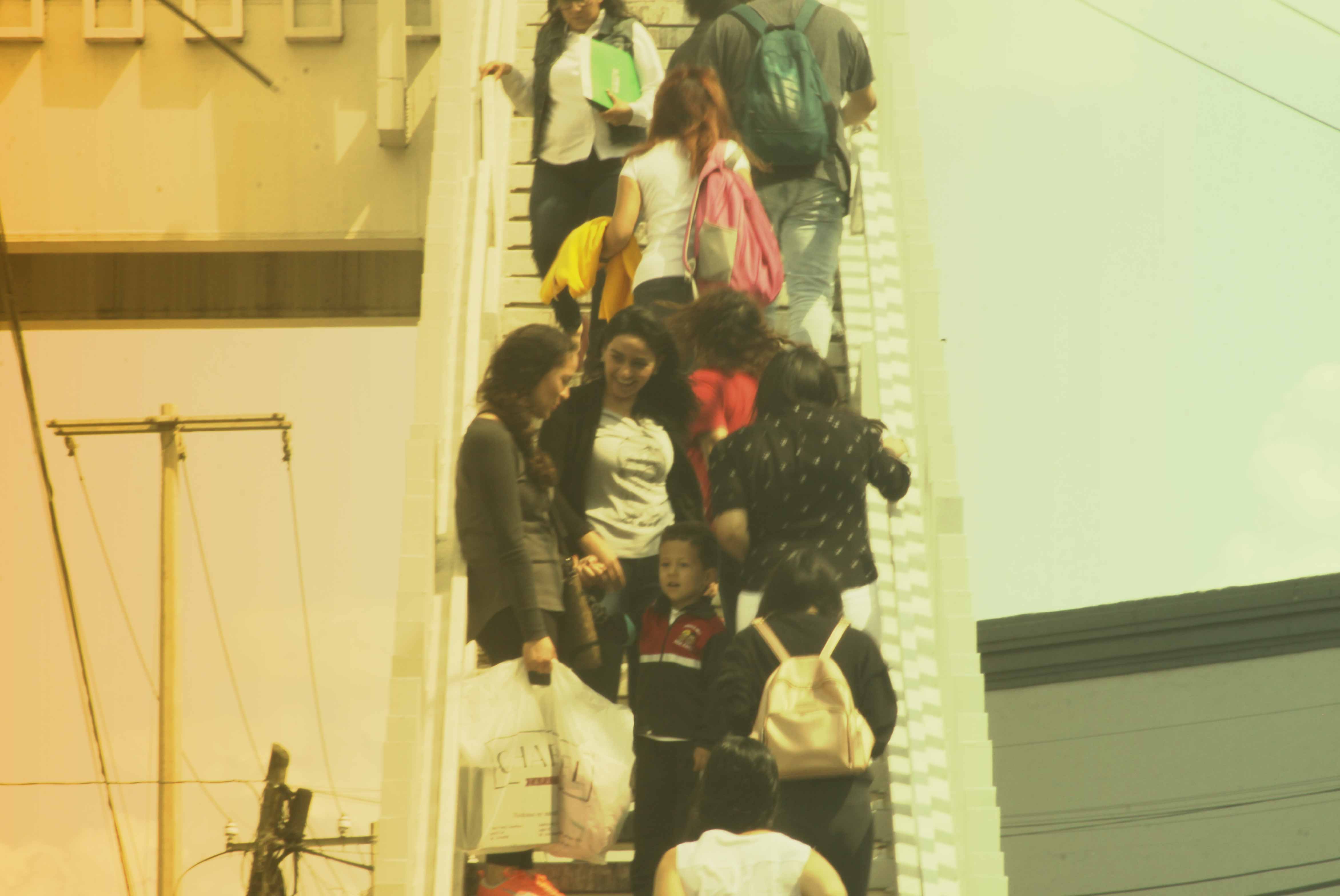 Mujeres y niño encontrándose en escaleras congestionadas de un puente antipeatonal